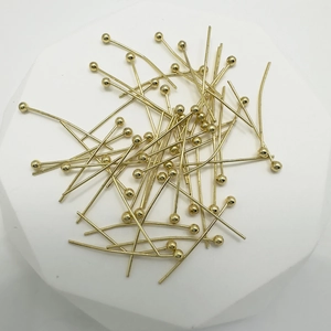 Golden brass ball head pins for DIY jewelry making displayed on a modern white stand