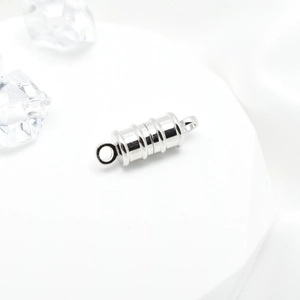 Silver cylindrical magnetic jewelry clasp for necklaces and bracelets on white stand