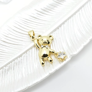 18k gold plated bear pendant with star zircon stone on a white ceramic tray