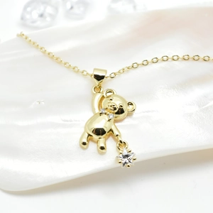 18k gold plated bear pendant necklace with zircon stars on a pearlescent shell background