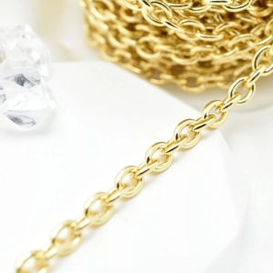 Golden oval link chain for DIY jewelry making and bags, macro view on white pedestal