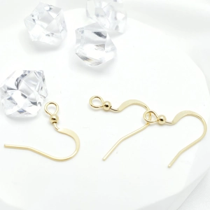 Ganchos dorados pulidos con cuenta para joyería DIY en soportes de exhibición blancos