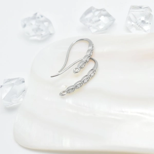 Crochets d'oreilles pois en argent avec zircons sur fond de coquillage marin