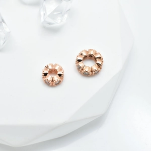 Makroaufnahme von roségoldenen gewellten Abstandsperlen mit Zirkonia-Einlage für Schmuck
