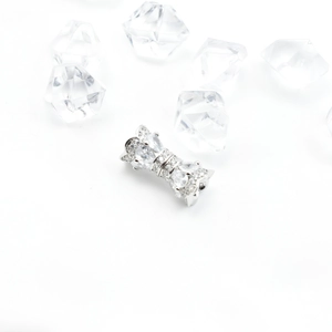 Macro shot of silver bow pendant with micro-pave cubic zirconia on ice cubes