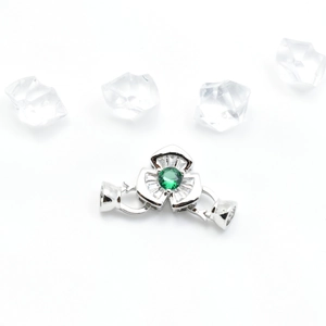 Détail du fermoir fleur en argent avec pierre verte et zircons baguette scintillants