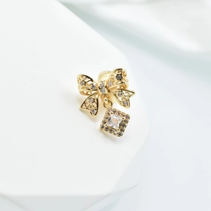 Golden bow pendant with hollow filigree work and square sparkling gemstone detail