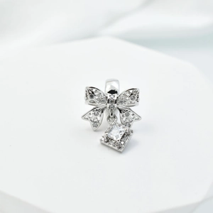 Silver bow pendant with sparkling cubic zirconia on a white geometric display stand