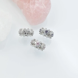Floral cylinder bead charms with colorful zircons on a clean white surface
