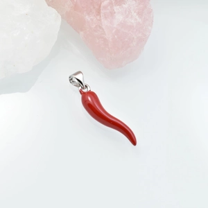 Vibrant red chili pepper pendant with silver clasp on a decorative stone background