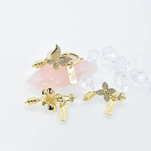 Golden butterfly and clover jewelry clasps with zircon pave on white background
