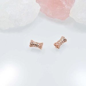 Elegant rose gold bow stud earrings with white zircon stones on white reflective surface