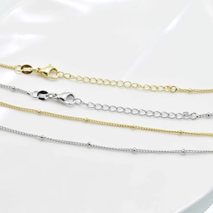Dettaglio di collane con perline in oro 18k e argento con chiusura a moschettone