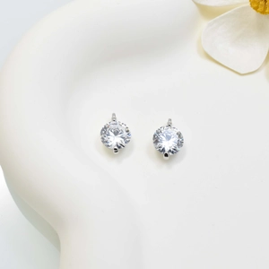 Elegant zircon stud earrings with silver setting on a white ceramic decorative tray