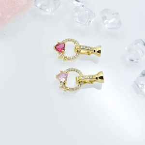 Macro detail of heart-shaped pink zircon jewelry connectors with gold plating