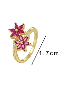 Dettaglio anello a fiore dorato con petali in zircone rosso e zirconi laterali incastonati