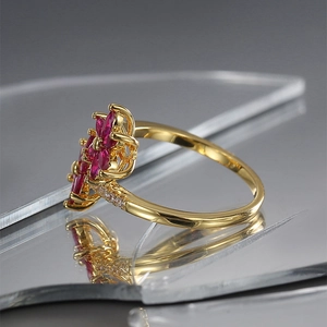 Elegante anello d'oro con fiori di zircone rosa su una superficie riflettente