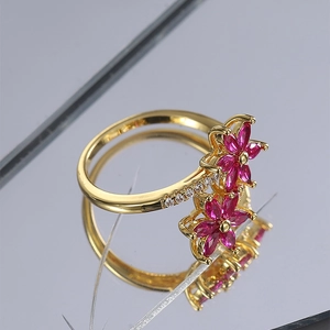 Dettaglio dell'anello a fiore dorato con petali marquise rosa e dettagli in zircone