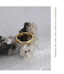Detail showing high-polish gold plated ring surface on a textured white stone base