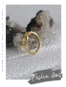 Detailed close-up of golden asymmetric knot ring with striped texture on stone background