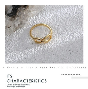 Detail of a gold-plated asymmetric ring featuring twisted rope and smooth metal textures