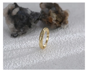 Detailed close-up of a gold signet ring featuring an eight-pointed star and tiny zircon