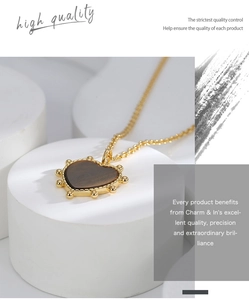 Macro shot of gold heart necklace featuring tiger eye stone on a white pedestal