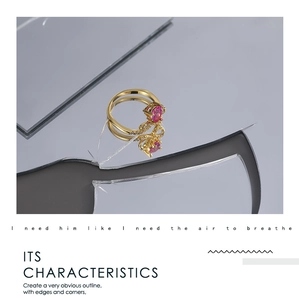 Detalle artístico de anillo dorado con piedra de corazón rosa sobre fondo de espejo roto