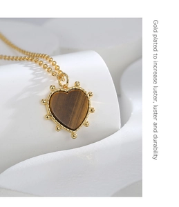 Macro shot of tiger eye heart pendant necklace featuring elegant golden bead edging detail