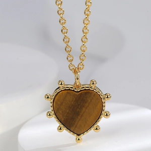 Macro shot of tiger eye heart pendant with vintage gold beaded edges and fine chain