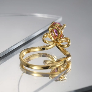Elegante anillo dorado con circón rosa en forma de pera y detalle de lazo fino