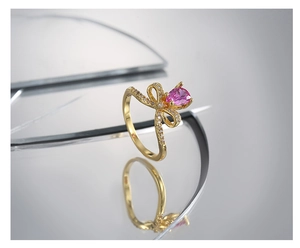 Detalle macro de anillo de lazo dorado con piedra rosa de pera y circonitas micro-pave