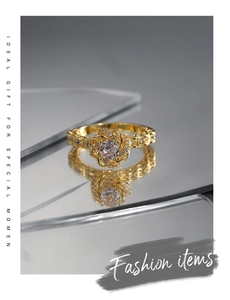 Macro shot of gold flower ring with center zircon and paved diamonds on a reflective surface