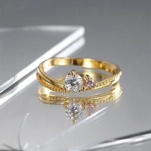 Gold ring featuring clear and pink zircons on a split band with bead edge textures