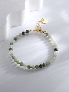 Macro detail of bead bracelet with green stones, gold lobster clasp and extension chain
