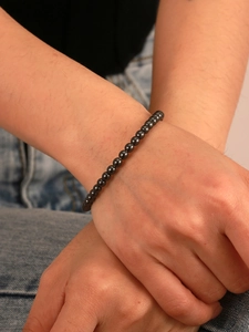 Close-up of a minimalist hematite beaded bracelet on a wrist with metallic luster