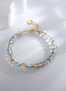 Détail macro de perles irisées colorées et du fermoir mousqueton doré sur le bracelet