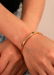 Detailed macro of a gold-plated brass cuff bracelet featuring four inlaid zircons