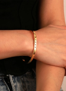 Detailed view of a gold-plated brass cuff bracelet set with four round zircon stones