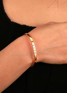 Macro view of minimalist gold-plated brass bracelet with four cubic zirconia stones