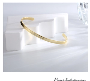 Detailed macro view of the micro inlaid zirconium stones on a gold-plated open bangle