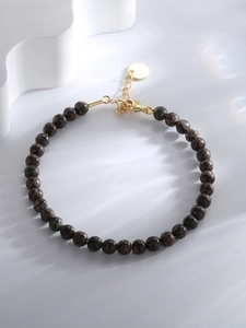 Macro shot of dark marbled beads and gold lobster clasp with adjustable chain links