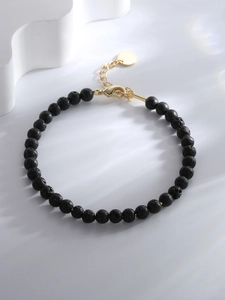 Detail of black lava stone beads with porous texture and golden adjustable lobster clasp