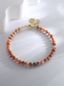 Close-up of beaded bracelet with orange marble stones and adjustable gold lobster clasp