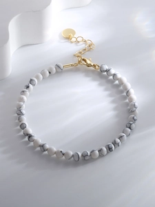 Detail of adjustable beaded bracelet with white marble stones and gold metal clasp