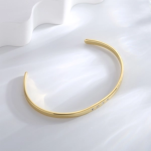 Minimalist gold plated brass open cuff bracelet featuring four zircon accents on polished metal