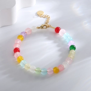 Bracelet en perles colorées avec fermoir mousqueton doré et chaîne de rallonge sur blanc