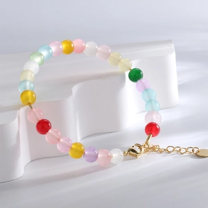 Bracelet en perles œil de chat colorées avec fermoir doré sur un support blanc minimaliste