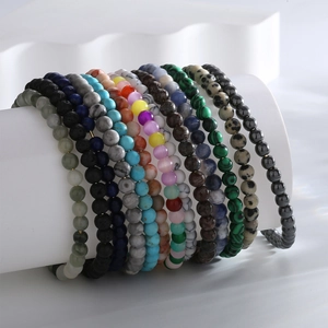 Stack of natural stone bead bracelets including malachite and tiger eye on white display