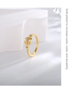 Macro shot of gold plated clover ring featuring zircon clusters and brushed metal texture